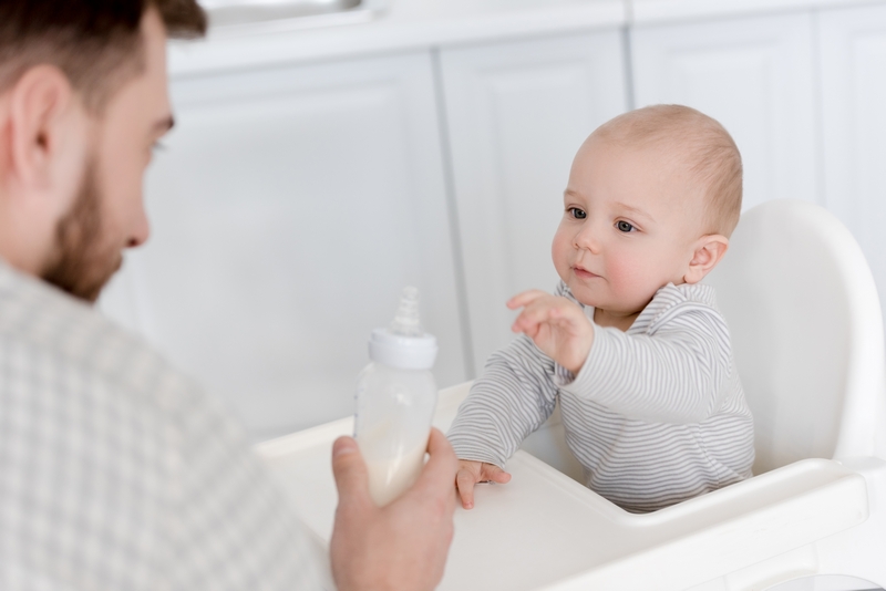 papa qui tend un biberon à son bébé