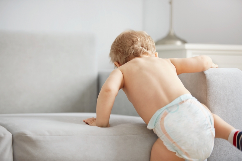 bébé qui monte sur le canapé