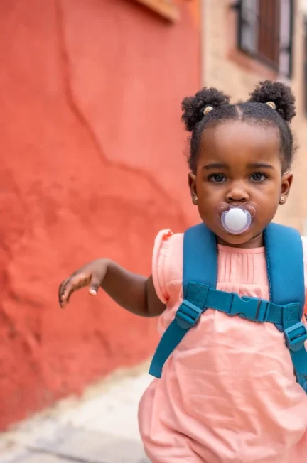 Une petite fille avec une tétine et un sac à dos