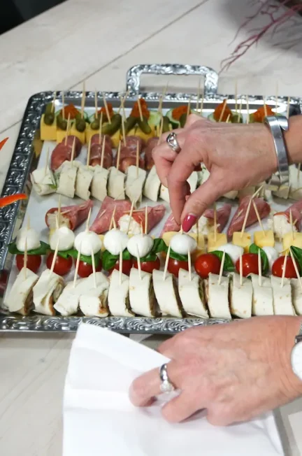 Une personne qui dresse des brochettes d'apéro sur un plateau